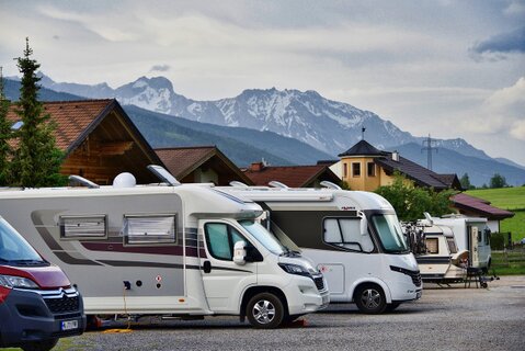 Mehrere verschiedene Wohnmobil-Typen nebeneinander auf einem Parkplatz